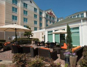 un patio con sillas y sombrillas frente a un hotel en Hilton Garden Inn Tallahassee Central en Tallahassee