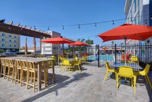 a patio with tables and chairs and red umbrellas at Home2 Suites By Hilton Panama City Beach, Fl in Panama City Beach