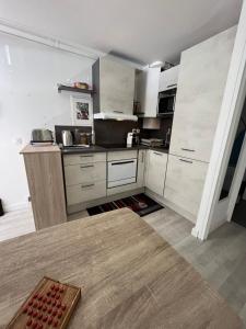 cocina con armarios blancos y mesa en Apartment cosy with terrace 200m from the sandy beaches wifi, en Juan-les-Pins