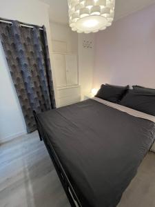 1 dormitorio con cama negra y lámpara de araña en Apartment cosy with terrace 200m from the sandy beaches wifi, en Juan-les-Pins