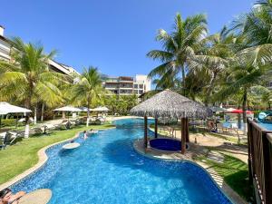 a swimming pool with palm trees and a resort at Beach Living - pé na areia, 200m do Beach Park in Aquiraz