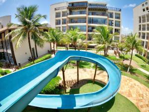 a blue slide in a park with palm trees at Beach Living - pé na areia, 200m do Beach Park in Aquiraz