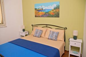a bedroom with a bed and a painting on the wall at A L' ARIA FRISCA - villetta a due passi dal mare in Torre Lapillo