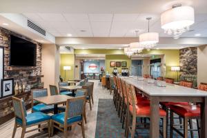 a restaurant with a long bar with chairs and tables at Hampton Inn Baltimore Bayview Campus in Baltimore