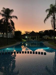une grande piscine avec des palmiers et un coucher de soleil dans l'établissement Casa Gayatri Teques, à Tequesquitengo