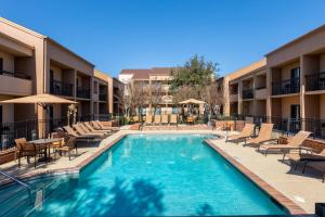 uma piscina num hotel com cadeiras e mesas em Courtyard by Marriott Dallas-Fort Worth/Bedford em Bedford