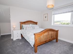 a bedroom with a wooden bed and a window at 4 Bodnant Road in Colwyn Bay