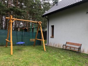een houten schommel met een bankje in een tuin bij Pod Lasem in Czarny Młyn