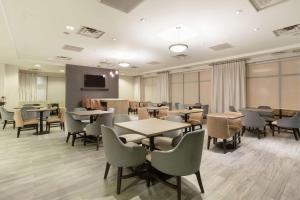 Hampton Inn & Suites Denver-Downtown في دنفر: غرفة انتظار مع طاولات وكراسي وتلفزيون