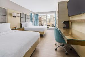 Hilton Garden Inn New York Times Square North في نيويورك: غرفة فندقية بسريرين ومكتب