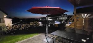 a table with a red umbrella on a patio at Sosnowe Domki in Sarbinowo