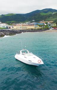 a white boat floating in the water near a beach at Sea & Tasty - Boat House in Ponta Delgada