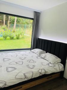 un letto in una camera da letto con una grande finestra di Tiny House by the forest “2” 