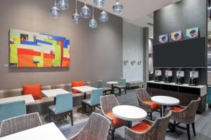 a restaurant with tables and chairs and a large screen at Hampton Inn & Suites Atlanta Buckhead Place in Atlanta