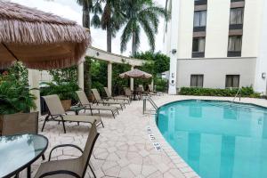 Una piscina con sillas y sombrillas al lado de un hotel. en Hampton Inn Boca Raton, en Boca Raton