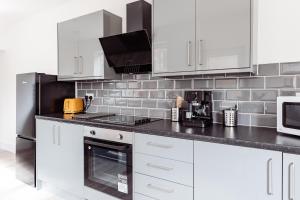 a kitchen with white cabinets and a black appliances at Brown Ball in Barrow in Furness