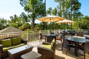 un patio con mesas, sillas y una sombrilla en Hilton Garden Inn Hilton Head en Hilton Head Island