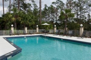 a swimming pool at a resort with chairs and trees at Hilton Garden Inn Hilton Head in Hilton Head Island