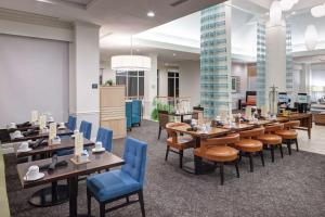 um restaurante com mesas de madeira e cadeiras azuis em Hilton Garden Inn Hilton Head em Hilton Head Island