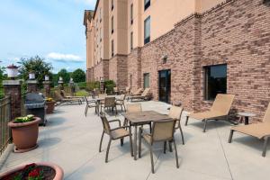 Hampton Inn & Suites Winston-Salem/University Area في وينستون سالم: فناء به طاولات وكراسي بجوار مبنى من الطوب