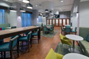 Hampton Inn & Suites Winston-Salem/University Area في وينستون سالم: غرفة انتظار مع طاولات وكراسي