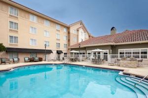 una piscina frente a un hotel con mesas y sillas en Homewood Suites by Hilton Jacksonville-South/St. Johns Ctr. en Jacksonville