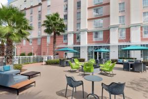 a patio with chairs and tables in front of a building at Hampton Inn & Suites Orlando Airport at Gateway Village in Orlando