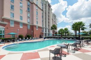 uma piscina num hotel com mesas e cadeiras em Hampton Inn & Suites Orlando Airport at Gateway Village em Orlando