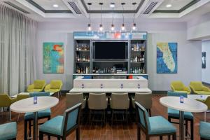 a bar in a restaurant with tables and chairs at Hampton Inn & Suites Orlando Airport at Gateway Village in Orlando
