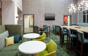 a lobby with tables and chairs and a tv at Hampton Inn & Suites Mobile I-65@ Airport Boulevard in Mobile