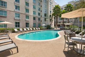 Homewood Suites by Hilton Tampa Airport - Westshore في تامبا: مسبح وكراسي وطاولات ومبنى