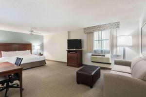 a hotel room with a bed and a couch and a tv at Homewood Suites by Hilton Tampa Airport - Westshore in Tampa