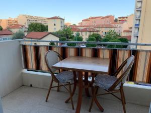 Una mesa de madera y dos sillas en un balcón. en Azzurra, en Menton