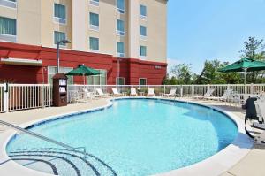 a pool in front of a hotel with chairs and umbrellas at Hampton Inn & Suites Knoxville-Turkey Creek Farragut in Knoxville