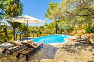 a swimming pool with two chairs and an umbrella at Villa Pelago in Skopelos Town