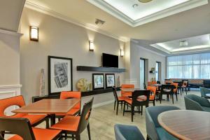 a restaurant with tables and chairs and a tv at Hampton Inn Palm Beach Gardens in Palm Beach Gardens