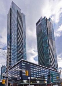three tall buildings in a city with a traffic light at Beautiful Unit in Heart of Downtown Toronto in Toronto