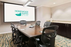 a conference room with a projector screen and a table and chairs at Homewood Suites by Hilton Bonita Springs in Bonita Springs