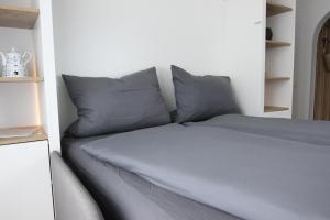 Inselbutze Borkum في بوركوم: سرير مع وسائد رمادية في الغرفة
