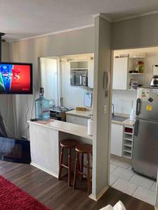 eine Küche mit einem Kühlschrank und einer Theke mit Stühlen in der Unterkunft Lindo apartamento cerca Del Mar. in La Serena