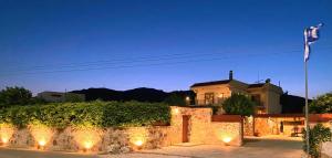 a house with a stone wall with lights and vines at Lucidum Rhodian Gastronomy Villa in Faliraki