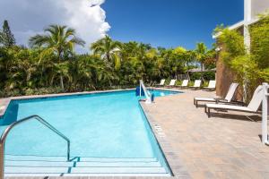 une grande piscine avec des chaises longues et des palmiers dans l'établissement Hilton Garden Inn Homestead, Fl, à Homestead