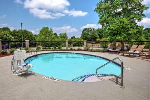una piscina con sedia e poltrona reclinabile accanto ad essa di Hampton Inn Charlotte/Matthews a Charlotte