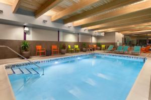 uma grande piscina com cadeiras e mesas coloridas em Home2 Suites by Hilton Champaign/Urbana em Champaign