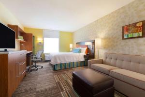 a hotel room with a bed and a couch at Home2 Suites by Hilton Champaign/Urbana in Champaign
