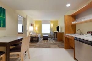 uma cozinha e sala de estar com mesa e cadeiras em Home2 Suites by Hilton Champaign/Urbana em Champaign