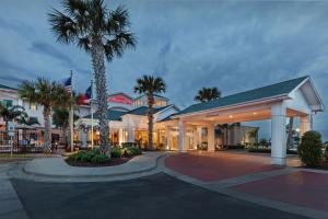 a hotel with palm trees in front of a building at Hilton Garden Inn Corpus Christi in Corpus Christi
