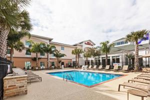 une piscine avec chaises longues et un hôtel dans l'établissement Hilton Garden Inn Corpus Christi, à Corpus Christi