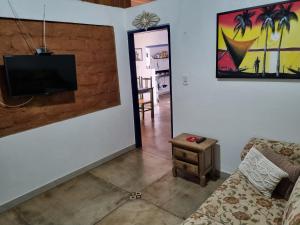 CASINHA AZUL/PIRINOPOLIS في بيرينوبوليس: غرفة معيشة مع أريكة وتلفزيون على الحائط