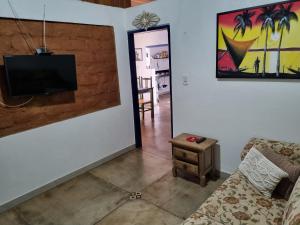 a living room with a couch and a tv on a wall at CASINHA AZUL/PIRINOPOLIS in Pirenópolis